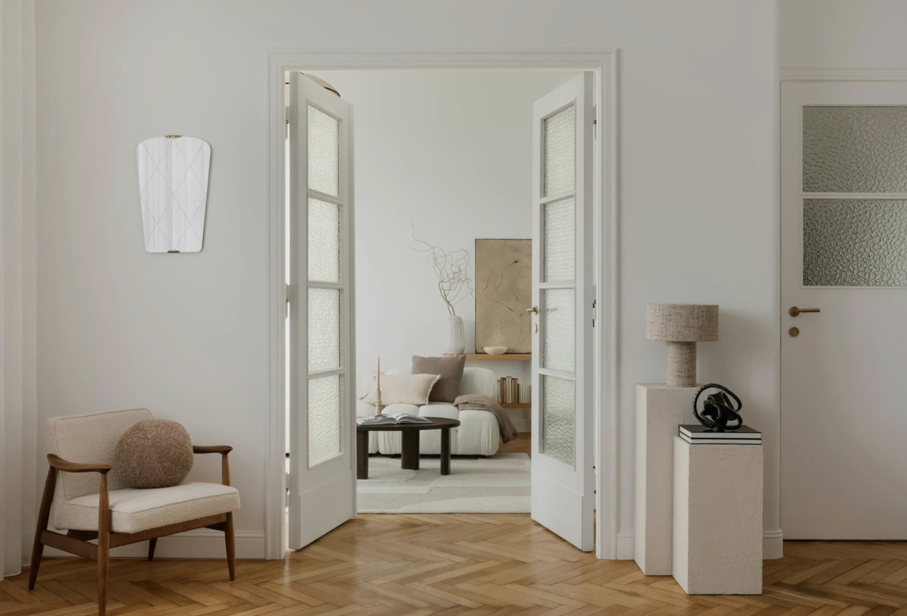 Open double doors leading from a bright hallway into a warm, softly furnished living room