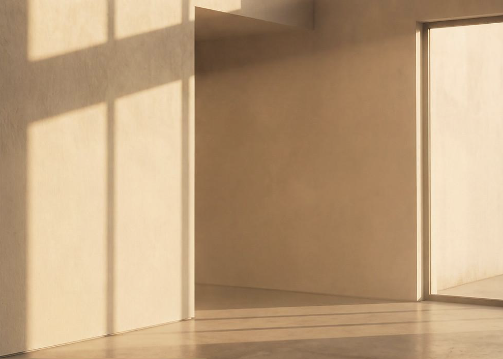 An empty, warm-toned room where afternoon sunlight casts geometric window shadows across plaster walls